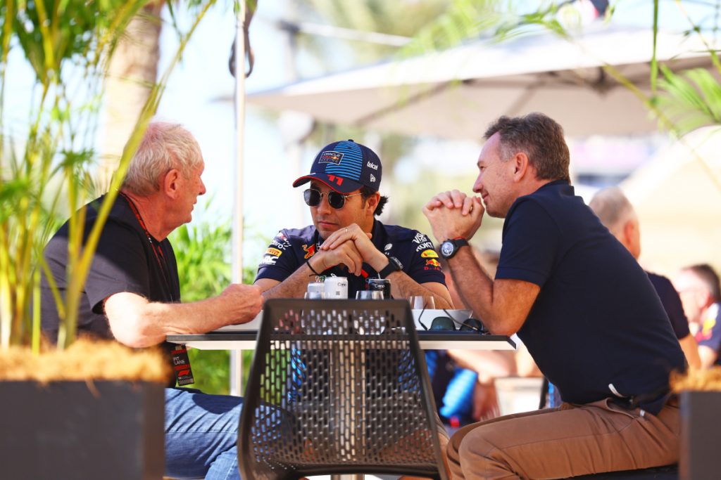 Checo sentado en una mesa con Horner y Marko hablando